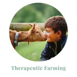 A young boy with glasses and a baby goat nuzzling his face.